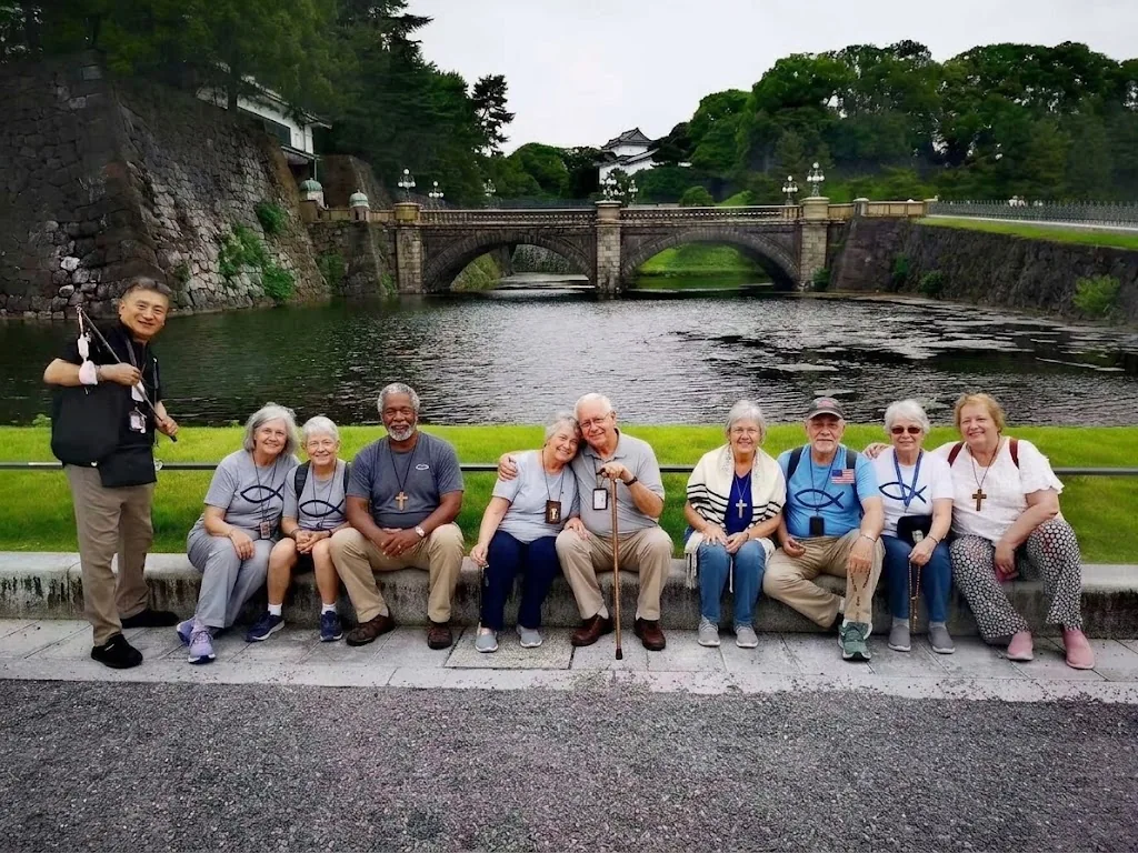 Pilgrims relaxing together beside the moat and stone bridge at the Tokyo Imperial Palace