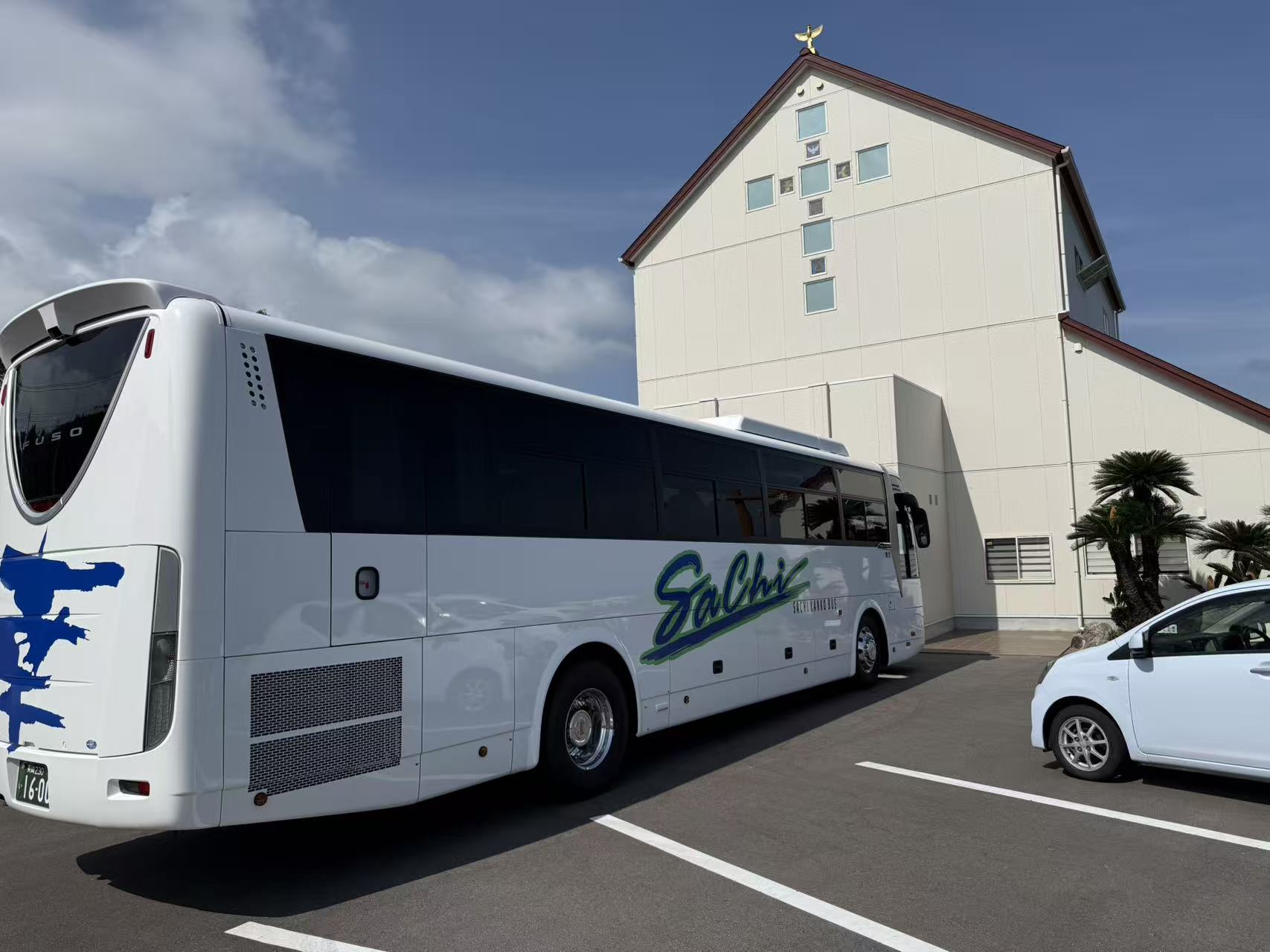 A luxury private coach parked beside a Catholic church in Japan