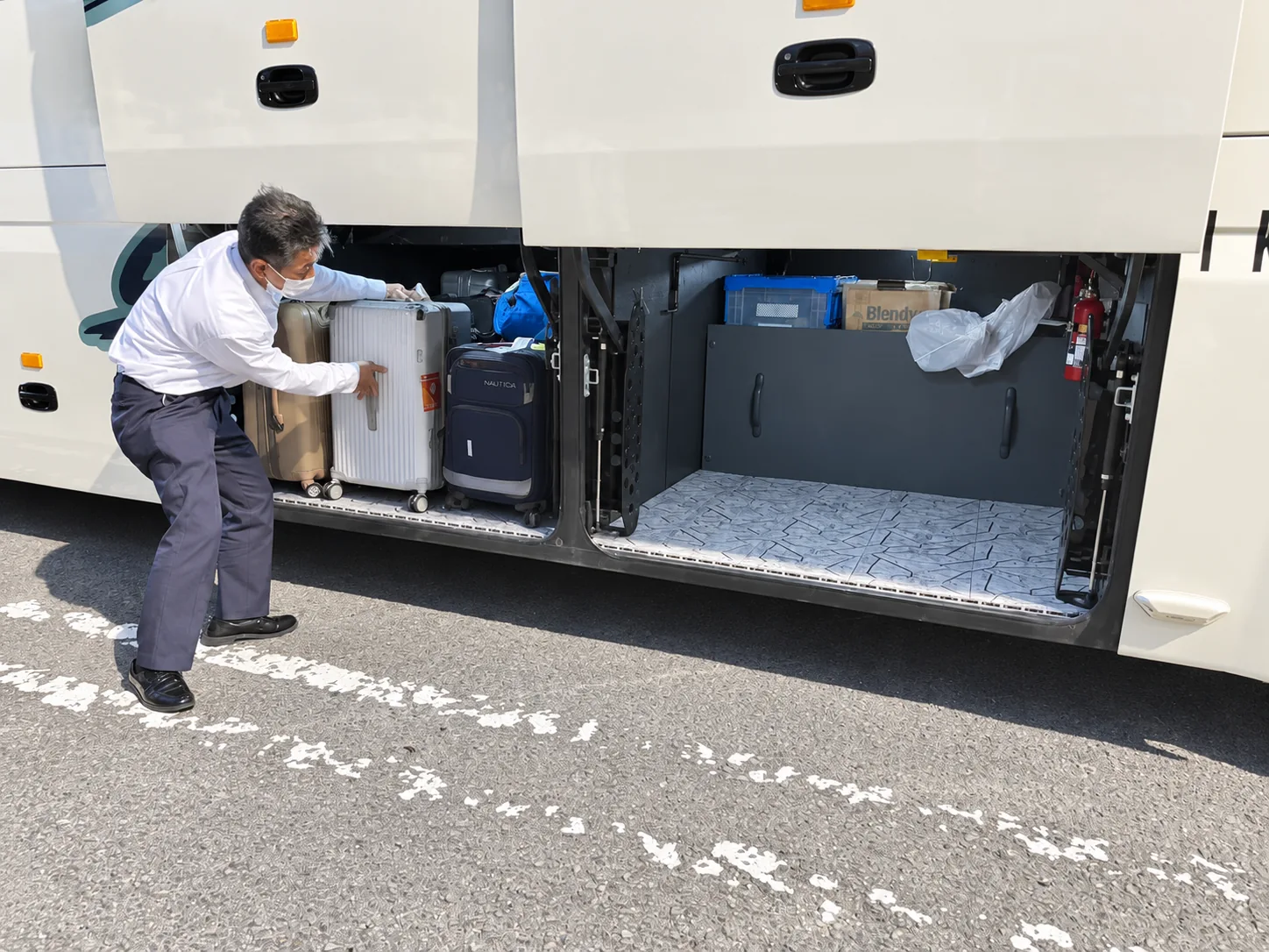 A professional coach driver carefully loading pilgrims’ luggage during the day