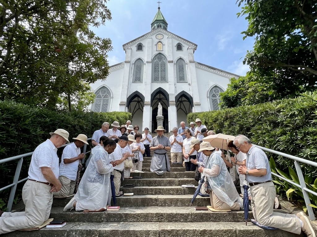Catholic pilgrimage group praying together on the steps of Ōura Cathedral in Nagasaki